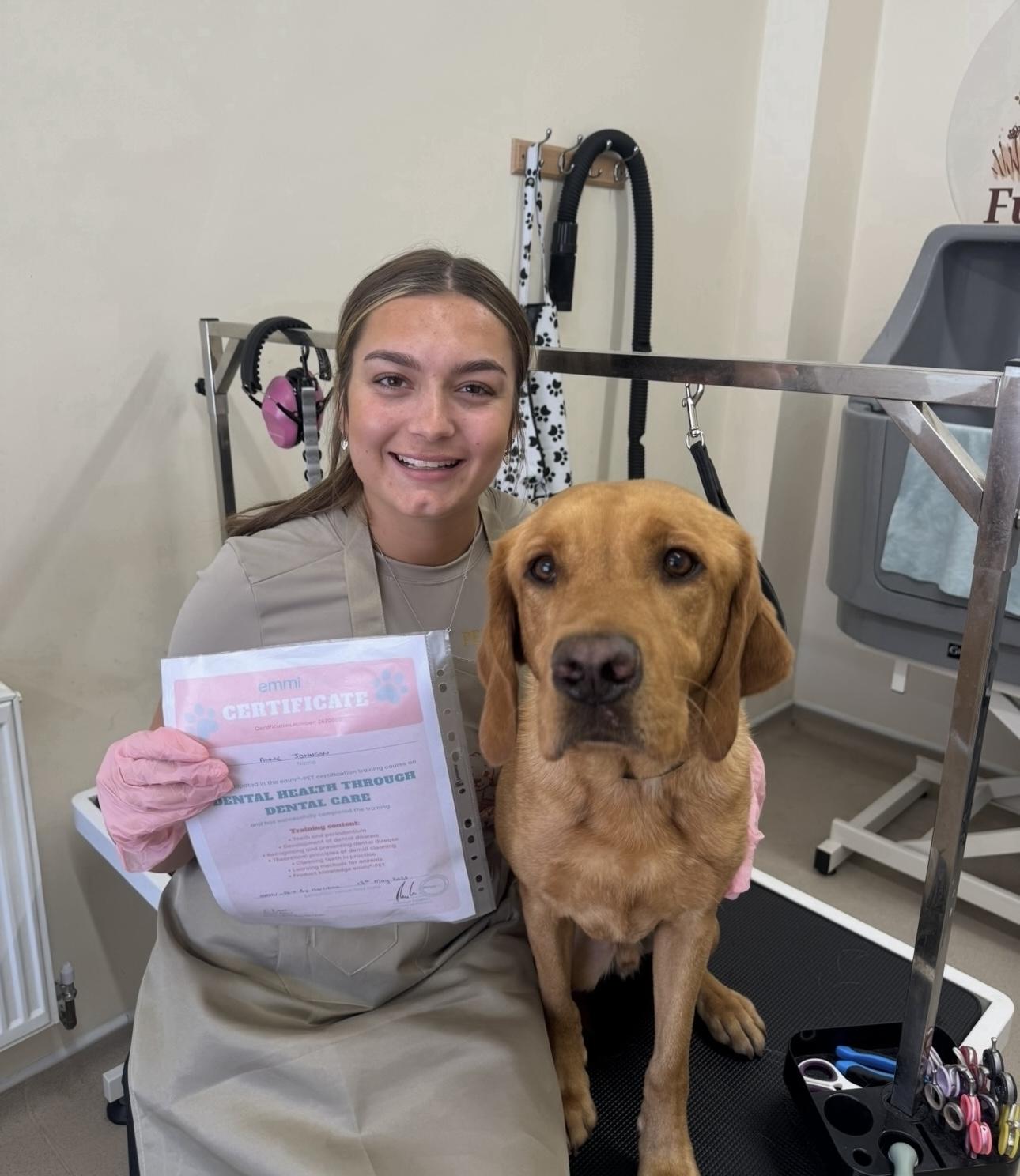 Annie with a ginger Labrador and her grooming certificate in the Fur&Fields salon.
